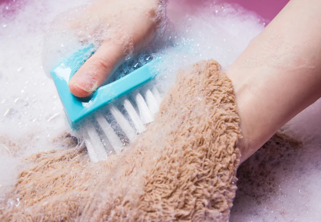 Pessoa lavando tapete na mão.